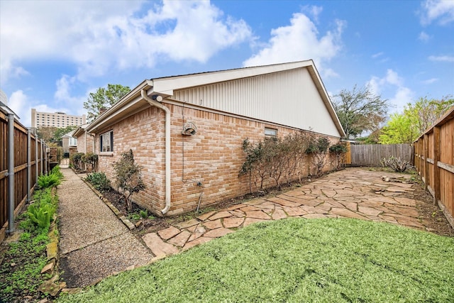 view of side of property featuring a patio and a lawn