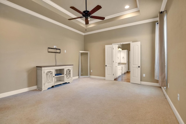 interior space with ornamental molding, a tray ceiling, a towering ceiling, ceiling fan, and carpet