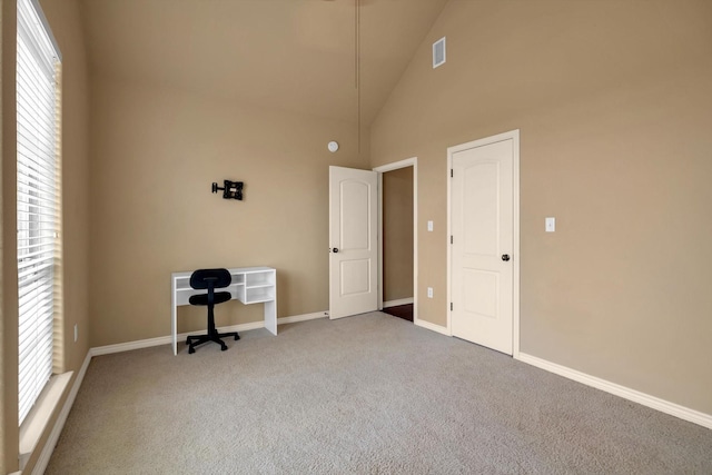 unfurnished office featuring carpet and high vaulted ceiling