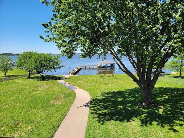 exterior space featuring a water view, a lawn, and a boat dock