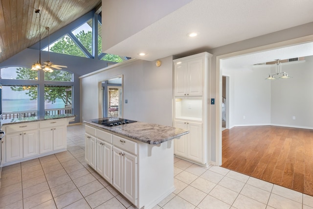 kitchen with light tile patterned flooring, a center island, white cabinets, and light stone counters