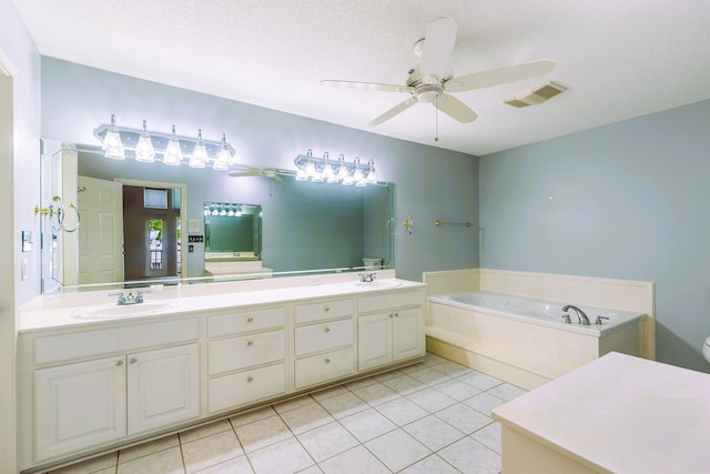 bathroom with a tub to relax in, toilet, a textured ceiling, vanity, and tile patterned flooring