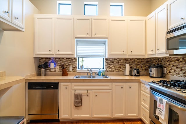 kitchen with white cabinetry, sink, backsplash, and stainless steel appliances