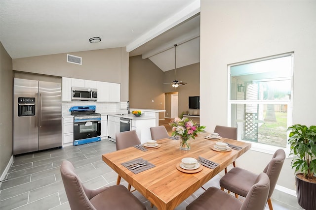 dining room featuring beamed ceiling, high vaulted ceiling, sink, and ceiling fan