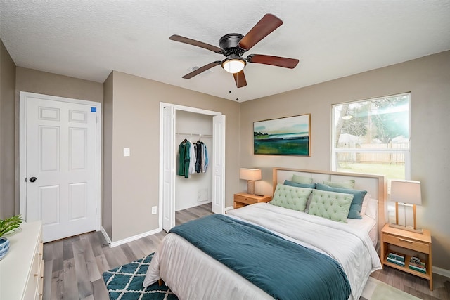 bedroom with ceiling fan, light hardwood / wood-style flooring, and a textured ceiling