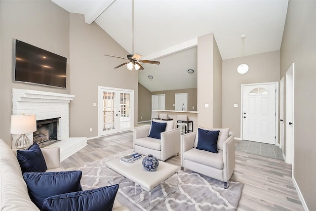 living room featuring ceiling fan, a fireplace, high vaulted ceiling, and light wood-type flooring