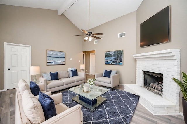 living room featuring high vaulted ceiling, a fireplace, beamed ceiling, hardwood / wood-style flooring, and ceiling fan