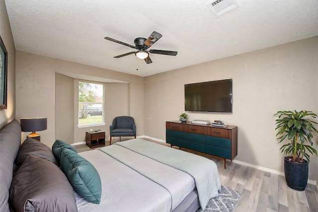 bedroom featuring ceiling fan, a textured ceiling, and light wood-type flooring