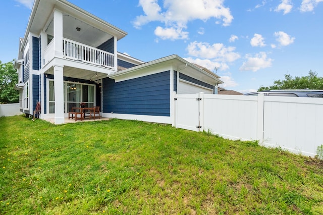 rear view of property with a balcony, a yard, and a patio