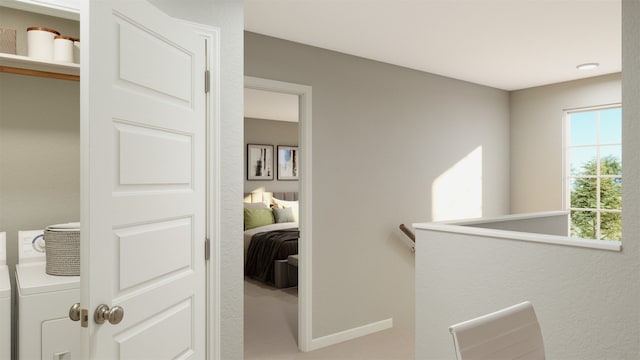 hallway with washer / clothes dryer, an upstairs landing, and baseboards