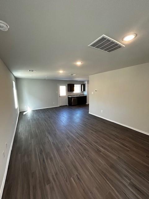 unfurnished living room featuring dark wood-style floors, visible vents, and baseboards