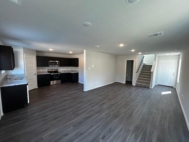 unfurnished living room with dark wood finished floors, recessed lighting, visible vents, baseboards, and stairs