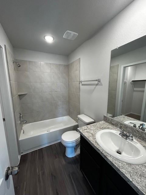 bathroom with toilet, washtub / shower combination, wood finished floors, and vanity