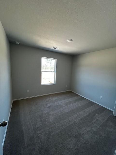 empty room with a textured ceiling, visible vents, and baseboards