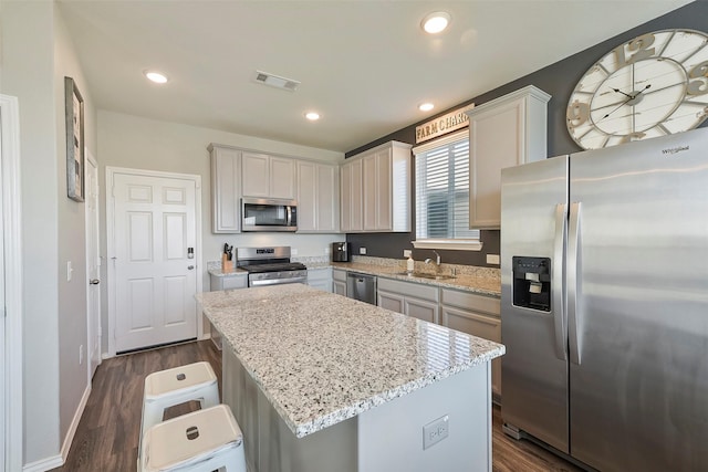 kitchen featuring a kitchen island, appliances with stainless steel finishes, sink, a kitchen bar, and light stone countertops