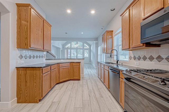 kitchen with sink, tasteful backsplash, light hardwood / wood-style flooring, kitchen peninsula, and stainless steel appliances