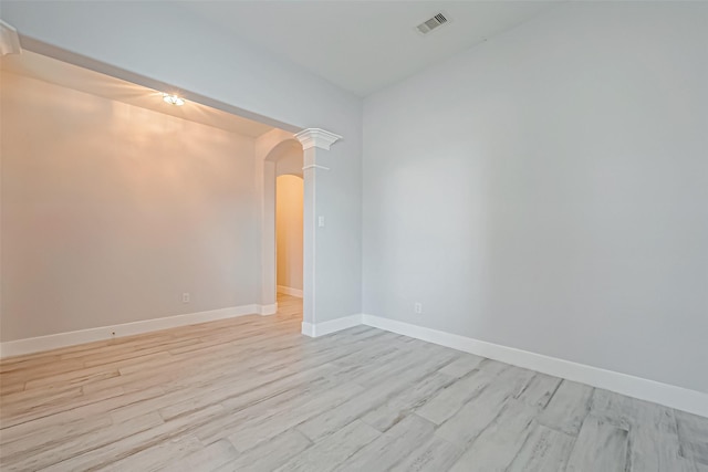 unfurnished room featuring light hardwood / wood-style flooring and ornate columns