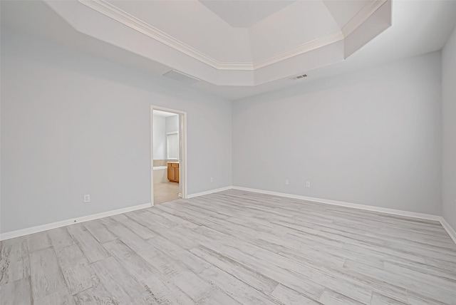 spare room featuring ornamental molding, a tray ceiling, and light wood-type flooring