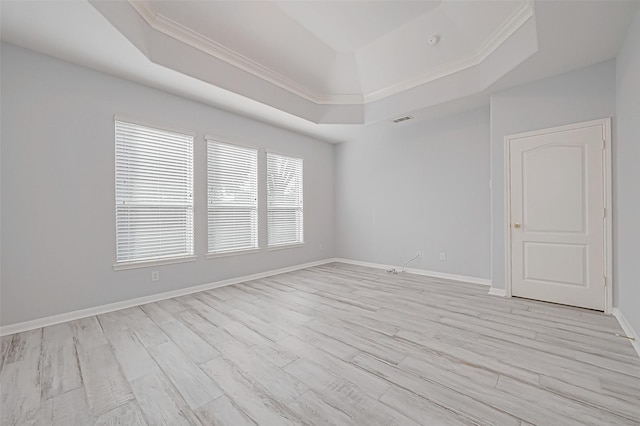 spare room with ornamental molding, light hardwood / wood-style flooring, and a tray ceiling