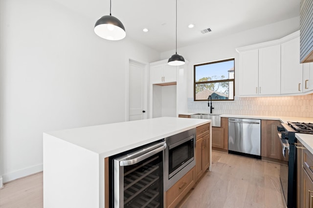 kitchen featuring stainless steel appliances, a kitchen island, white cabinets, and beverage cooler