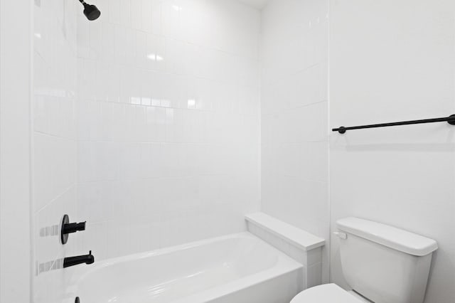 bathroom featuring tiled shower / bath combo and toilet