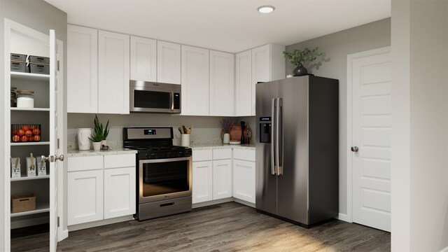 kitchen with white cabinetry, appliances with stainless steel finishes, light stone counters, and dark hardwood / wood-style flooring