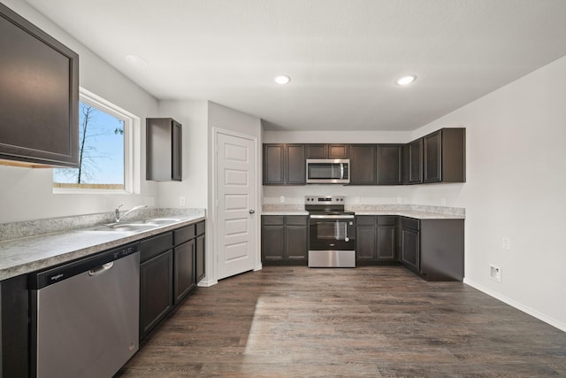 kitchen with dark wood finished floors, stainless steel appliances, recessed lighting, light countertops, and a sink