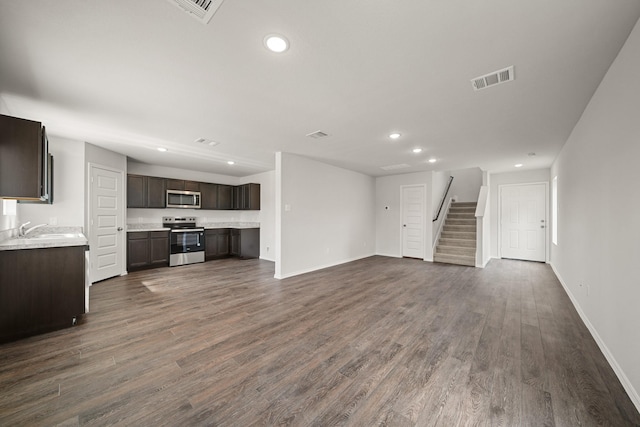 unfurnished living room featuring recessed lighting, a sink, visible vents, stairway, and dark wood finished floors