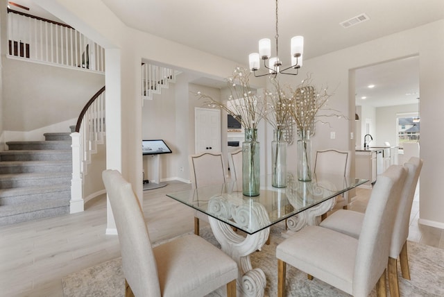 dining area featuring sink, light hardwood / wood-style flooring, and a notable chandelier