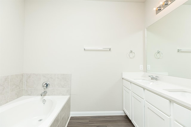 bathroom with vanity, tiled tub, and hardwood / wood-style floors