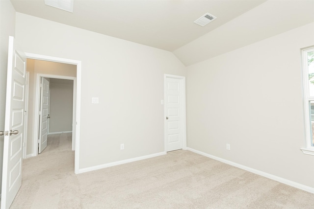 carpeted spare room with vaulted ceiling