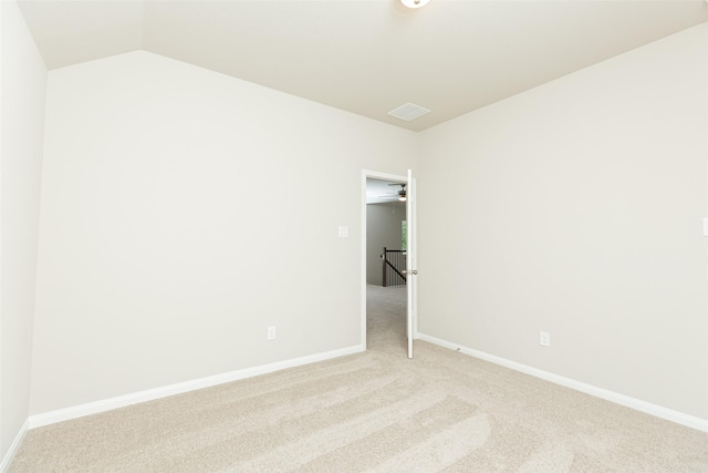 carpeted spare room featuring vaulted ceiling