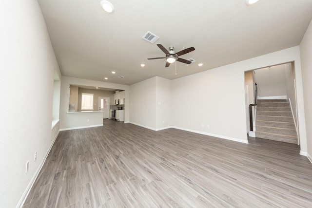 unfurnished living room with recessed lighting, visible vents, stairway, wood finished floors, and baseboards