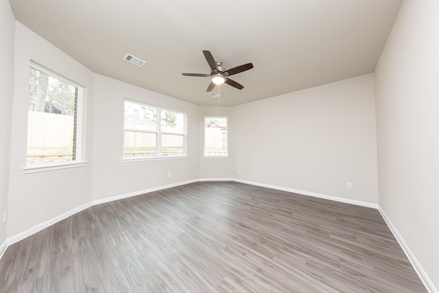 spare room with ceiling fan, wood finished floors, visible vents, and baseboards