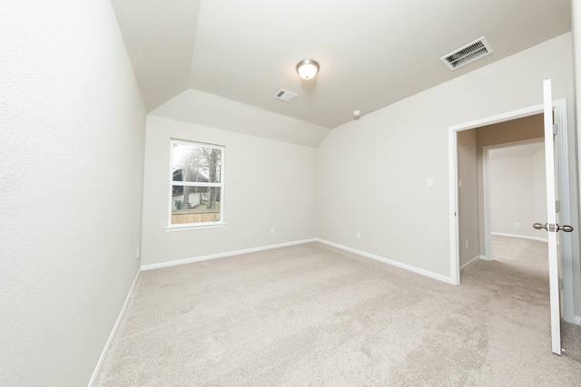 spare room with lofted ceiling, visible vents, light carpet, and baseboards