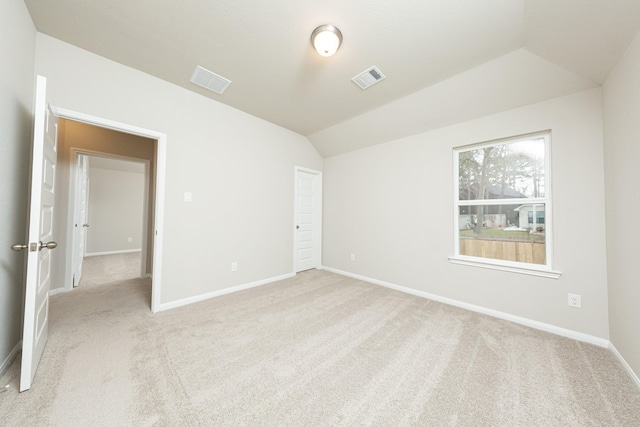 carpeted spare room featuring vaulted ceiling, visible vents, and baseboards