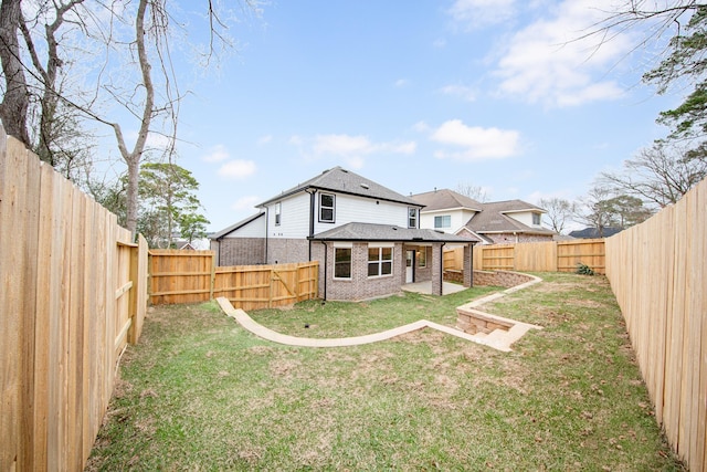 rear view of house featuring a yard, a fenced backyard, and brick siding