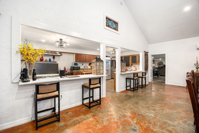 kitchen with concrete flooring, high vaulted ceiling, a kitchen breakfast bar, and kitchen peninsula