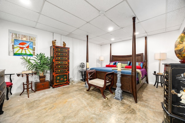 bedroom featuring concrete flooring and a drop ceiling