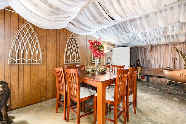 dining space featuring concrete flooring and wood walls