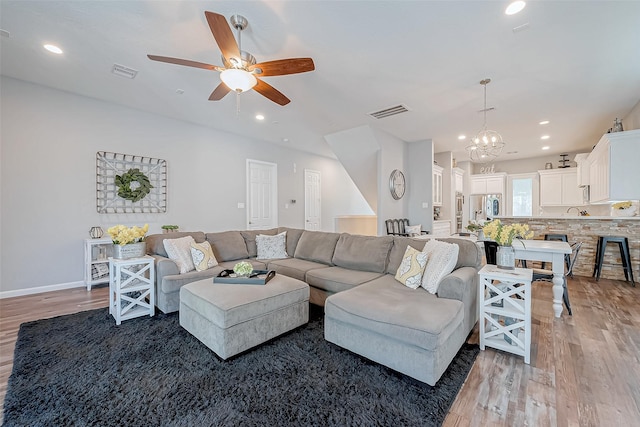 living room with ceiling fan with notable chandelier and wood-type flooring