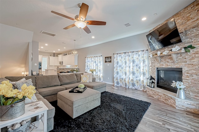 living room with ceiling fan, a fireplace, and light hardwood / wood-style flooring