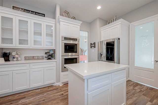 kitchen featuring stainless steel appliances, white cabinets, light wood-type flooring, and decorative backsplash