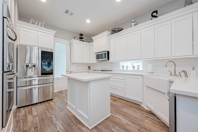 kitchen featuring light wood-type flooring, a center island, white cabinets, and appliances with stainless steel finishes