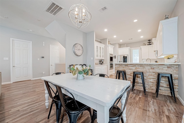 dining area with sink, a chandelier, and light hardwood / wood-style flooring