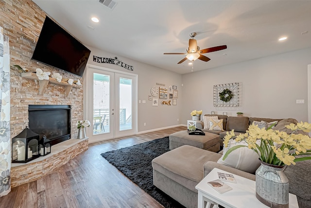 living room with a fireplace, wood-type flooring, french doors, and ceiling fan