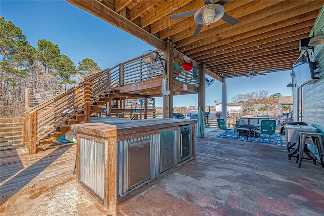 view of patio / terrace with a wooden deck, exterior kitchen, ceiling fan, and exterior bar