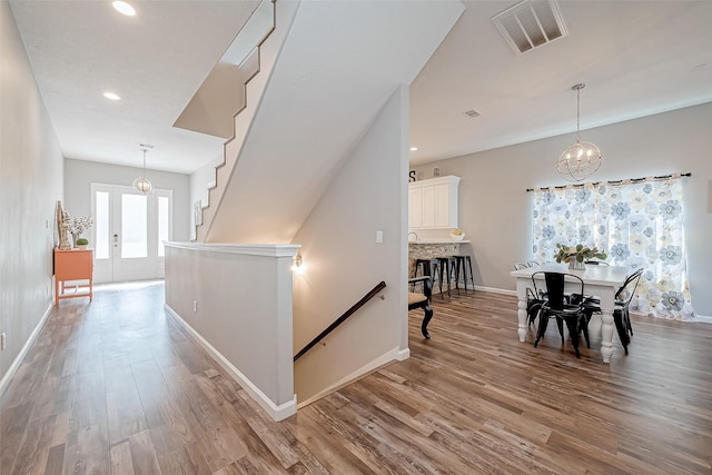 hallway featuring an inviting chandelier, french doors, and light wood-type flooring