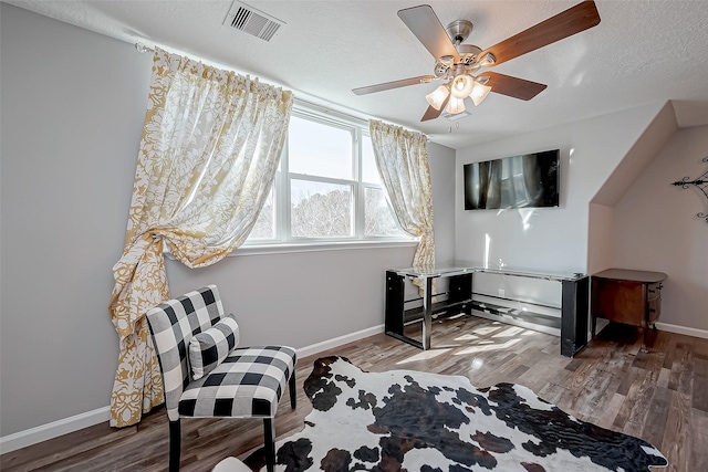 living area with hardwood / wood-style flooring, ceiling fan, and a textured ceiling