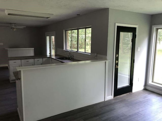 kitchen with white cabinetry, dark hardwood / wood-style flooring, kitchen peninsula, and sink